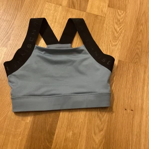 Ljusblå sport-bh från Röhnisch - Säljer en ljusblå sport-bh från Röhnisch med breda svarta axelband med logga. Bh:n har en sportig design och är perfekt för träning. Materialet känns mjukt och stretchigt för bra komfort.💕Jag beställde den men den vart alldeles för liten för mig, jag tappade bort kvittot.