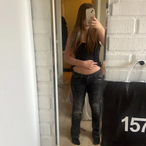 Svarta slitna jeansbyxor - Säljer ett par svarta jeansbyxor med slitningar på båda benen. Byxorna har ett liten hål i rumpan men det går enkelt att laga själv, jeansen är low waist och boot cut💞