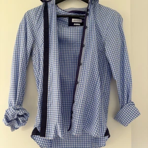 Blårutig skjorta från J. Harvest & Frost - Säljer en klassisk blårutig skjorta från J. Harvest & Frost i storlek S (36). Skjortan är tillverkad i 100% bomull, har långa ärmar och knappar framtill. Perfekt för en stilren och tidlös look. Som ny!