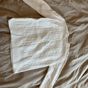 Vit kabelstickad tröja från H&M - Säljer en vit kabelstickad tröja från Zara som aldrig är använd eller som har används få antal gånger. Tröjan har rund halsringning och långa ärmar. ett klassiskt kabelstickat mönster som passar perfekt till både vardag och lite finare tillfällen. Hör gärna av dig vid frågor! 