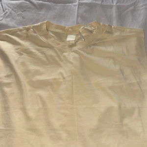 Gul t-shirt från H&M - Säljer en basic Gul t-shirt från H&M. T-shirten har rund halsringning och är tillverkad i mjuk bomull. Perfekt att styla med jeans eller shorts för en enkel och clean look.