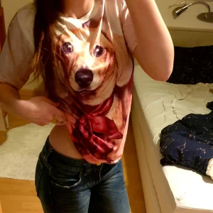 T-shirt med tax-tryck och röd rosett - Cool och urgullig t-shirt med stort tryck av en tax med röd rosett på framsidan. T-shirten är färgglad med korta ärmar och har en avslappnad passform. Perfekt för dig som gillar hundar och vill sticka ut med en unik look. Supermysigt material och endast använd ett fåtal gånger.