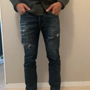Levi's 511 Slim jeans blå - Säljer ett par Levi's 511 Slim jeans i mörkblå tvätt med slitna detaljer på benen. Klassisk femficksmodell med dragkedja och slim passform. Jeansen är Levis ”Blue Tab” och en är exklusiv och dyrare lodell.