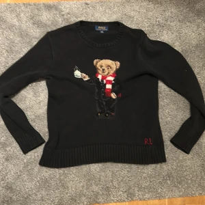 Svart stickad tröja från Polo Ralph Lauren. - Svart stickad tröja från Polo Ralph Lauren med en broderad björn på framsidan. Tröjan passar perfekt för vardags bruk och festligare bruk. Storleken är 14-16 men passar 150-165. Nypris 2300. Mitt pris 499 priset är ej hugget i sten. Skickar snabbt 💨 