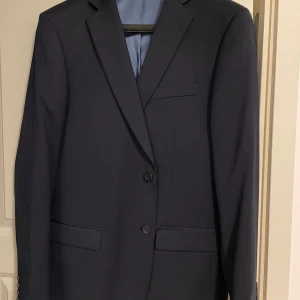 Mörkblå kostym från Dressmann, slim fit - Säljer en mörkblå kostym från Dressmann i slim fit-modell. Knappt använt max 2 gånger. Säljs då den inte passar längre. 
