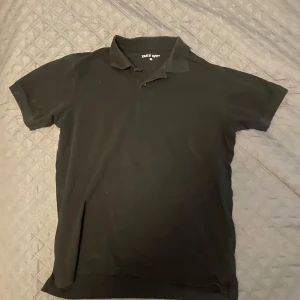 Svart pikétröja från Take Off - Säljer en klassisk svart pikétröja från Take Off i storlek M. Tröjan har korta ärmar, krage och knäppning framtill. Perfekt för en stilren och enkel look. Materialet känns mjukt och bekvämt mot huden.