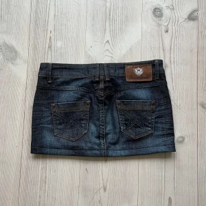 Blå lågmidjad jeanskjol  - Mörkblå lågmidjad jeanskjol från Freeman T. Porter i storlek S. Tvärs över midjan är det 39 cm och den är 27 cm lång. Fint skick. Använd gärna köp nu!