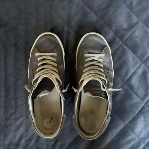  Sneakers från Philippe Model - Säljer ett par gråbruna Philippe Model sneakers för endast 500 kr. Skorna är i ganska dåligt skick se bilder men fungerar fortfarande att använda om man vill ha ett par schyssta vardagssneakers utan att bry sig för mycket om slitaget, billigare alternativ till helt nya och skadorna är inte omfattande  Observera att sulorna på insidan är trasiga och att skorna säljs i befintligt skick. Skokartong från Philippe Model medföljer