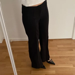Svarta bootcut-byxor från H&M - Säljer ett par svarta bootcut-byxor från H&M i storlek 38. Byxorna har en klassisk passform med utsvängda ben och stängs med knapp och dragkedja framtill. Perfekta till många olika stilar och enkla att matcha.