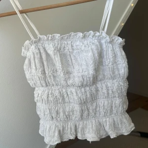Vit broderad croppad linnetopp - Säljer en söt vit croppad linnetopp med smala axelband och volangkant. Går att ha som tubtopp också❣️