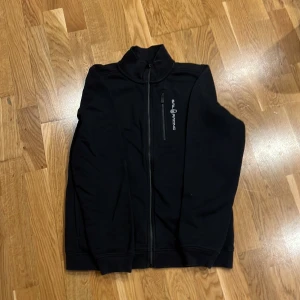 Svart hoodie från Sail Racing med dragkedja - Helt oanvänd stil racing bowman zip jacket försökte skicka tillbaka till zarlando men hade de gick för lång tid imellan så säljer den istället köpte för 899 men säljer för endast 400