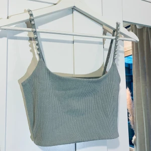 Gråblå ribbad croppad linnetopp med pärlband - Snygg gråblå croppad linnetopp från Zara med ribbad struktur och axelband dekorerade med pärlor. Perfekt för att lyfta en outfit med en trendig detalj. Skriv för fler bilder🩵