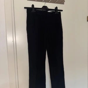 Svarta kostymbyxor från Boss - Säljer ett par klassiska svarta kostymbyxor från Boss. Byxorna har rak passform och är tillverkade i ett mjukt material som känns bekvämt. Perfekta för en stilren look och passar till många olika tillfällen.
