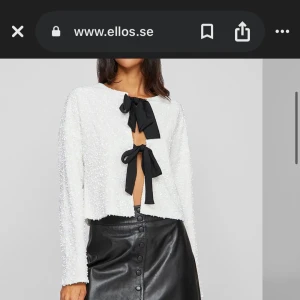 Vit paljettkofta med svarta rosetter från Ellos - nypris 549. Säljer en vit, glittrig kofta med paljetter och två stora svarta rosetter framtill. Koftan är croppad och har långa ärmar. Perfekt för dig som vill sticka ut med en trendig och söt look! 