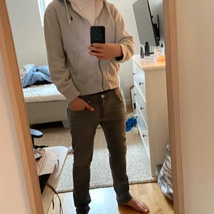 Grå hoodie med dragkedja från Polo Ralph Lauren - Grå hoodie från Polo Ralph Lauren med dragkedja och huva. Klassisk design med fickor framtill och vit dragsko. Liten broderad logga på bröstet. Du får ovkså med byxorna om du skulle vilka för 100kr mer! Sliten vid slutet av armarna men inget som man tänker på!