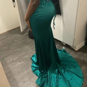 Grön lång balklänning med släp - Säljer en jätte snygg smaragdgrön långklänning i glansigt material som jag hade på balen😍