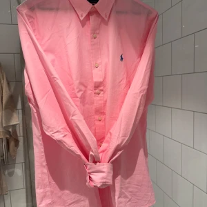 Rosa skjorta från Polo Ralph Lauren - 3 veckor gammal Poplin rosa skjorta från Polo Ralph Lauren i slim fit-modell. Nyskick (kvitto ingår) normal i storleken.