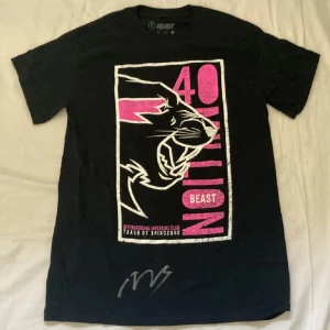 Svart t-shirt med mrbeasts signatur  - Cool svart t-shirt med stort pantermotiv och text i rosa och vitt på framsidan. Trycket har texten '40 Million', 'Beast' och 'International Investors Club'. Perfekt för dig som gillar streetwear och unika prints. Signerad av Mrbest på livestream              Pris går att diskutera 