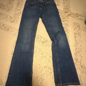Blå bootcut jeans från Zara - Säljer ett par klassiska blå bootcut jeans från Zara i storlek 38. Jeansen har normal passform, dragkedja och knapp framtill samt fem fickor. Perfekta till dig som gillar en tidlös jeanslook. De är stretchiga i midjan så passar S-M. Trendiga jeans!😍