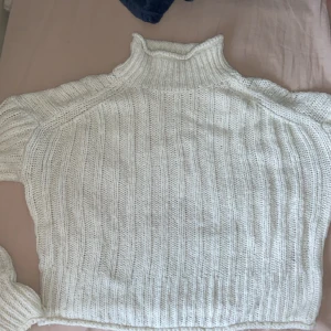 Vit stickad polotröja - Mysig vit stickad polotröja med ribbat mönster. Tröjan har lång ärm och hög polokrage, perfekt för kyliga dagar. Passar till allt och är superenkel att styla.