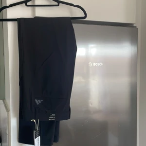 Svarta golfbyxor från Adidas - Säljer ett par svarta golfbyxor från Adidas med regular fit och tapered ben.  Helt oanvända med alla lappar och kvitto finns. Nypris 900