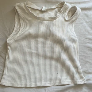 Vit ribbad linnetopp - Säljer en vit ribbad linnetopp med rund halsringning. Toppen är ärmlös och har en croppad passform.