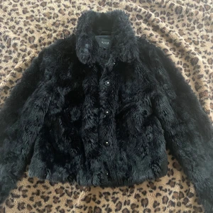 Svart pälsjacka från vila - Säljer en svart pälsjacka från vila med klassisk krage och knappar framtill. Jackan har lång ärm och är supermjuk med fluffig känsla. Perfekt för dig som vill sticka ut och hålla dig varm.