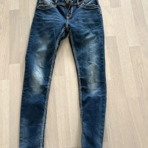 Blå skinny jeans från Amisu - Säljer ett par blå skinny jeans från Amisu med snygga slitningar och kontrastsömmar. Jeansen har klassisk femficksdesign och normalhög midja. Perfekta för dig som gillar en tight passform och stilren look.