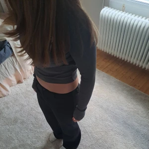 Mörkgrå croppad långärmad tröja från Bershka - Säljer en mörkgrå croppad långärmad tröja från Bershka. Tröjan är ribbad och har en tight passform med rund halsringning. Perfekt att matcha med höga jeans eller kjol🌸🎀