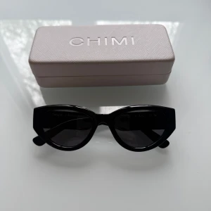 Svarta solglasögon från CHIMI 06 Black  - Stilrena svarta solglasögon från CHIMI i modellen 06 Black med markerad båge i cat-eye form. Kommer med originaletui och oanvänd putsduk✨Nypris 1400 kr 