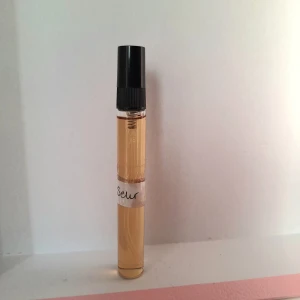 Ajmal Amber Wood Vanilla Parfymprov 10 ml, köpt I butik  - Parfymprov av Ajmal Amber Wood Vanilla i ett smidigt rör med svart lock. Doften har tydliga inslag av vanilj, mandel, sötma, varm krydda, amber, nötighet, oud, frukt, trä och kanel. Perfekt för dig som gillar lyxiga och unika doftnoter.