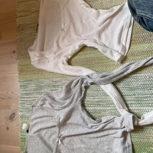 Vit ribbad långärmad topp med spets - Supersöt vit ribbad långärmad topp med spetskant och liten rosett vid urringningen. Figurnära passform och stretchigt material, perfekt att styla med jeans eller kjol. Urringningen är fyrkantig och dekorerad med spetsdetaljer för en extra feminin touch. 70kr för båda eller 50kr för en