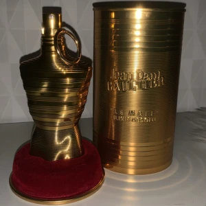 Jean Paul Gaultier Le Male Elixir absolu - Exklusiv parfym i metallisk guldflaska formad som en manlig torso, med tillhörande guldfärgad burk och röd sammetsbas. Le Male Elixir är en intensiv doft, 75ml, perfekt för dig som gillar lyxig design och starka intryck. 70ml/75ml