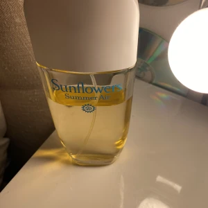 Sunflowers Summer Air parfym - Fräsch parfym från Sunflowers i varianten Summer Air. Flaskan är genomskinlig med gul vätska och har ett vitt lock. Doften är lätt och somrig, perfekt för dig som gillar blommiga och fruktiga toner.