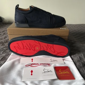 Mörkblå sneakers från Christian Louboutin - Snygga mörkblå sneakers från Christian Louboutin i mocka med klassisk röd sula och diskret logga på hälen. Perfekta för dig som vill sticka ut med exklusiv stil och ikonisk design. tillbehör finns med ⚠️Älthet kan ej garanteras-därav priset. 