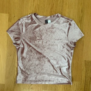 Rosa sammetstopp från Divided - Supermjuk och glansig rosa sammetstopp från Divided med broderad text 'pass the tissues we all got issues' framtill. T-shirten har rund halsringning och korta ärmar, perfekt för dig som gillar en chill men ändå snygg vibe.