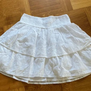 Vit volangkjol  - Superfin vit kortkjol med volanger och broderade detaljer. Storlek: S, Postar oftast mellan 1-2 dagar! Från Gina Tricot 