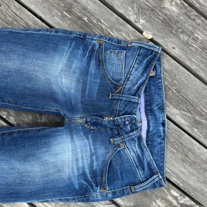 Blå bootcut jeans från Lee - Snygga blå bootcut jeans från Lee med klassisk femficksdesign och kontrastsömmar. Jeansen har en lätt tvättad look och lila detaljer på insidan av linningen. Tillverkade i bomull med en skön passform och normal midja.