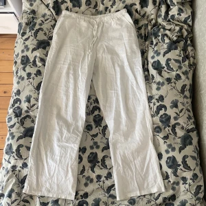 Vita linnebyxor från Gina Tricot - Säljer ett par vita linnebyxor från Gina Tricot med rak passform och resår i midjan. Byxorna har snörning i midjan och är tillverkade i svalt linnematerial, perfekta för varma dagar. Enkla fickor på sidorna och stilren look. Jag råkade beställa två och finns därför ett par exakt likadana i samma storlek i ett oöppnad paket, de är alltså dessa jag säljer. Passar mellan 160-170cm skulle jag säga🥰