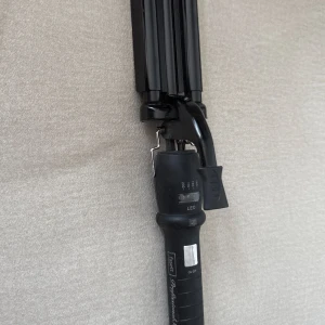 Svart Trippeltång från Fasett - En svart vågtång från Fasett med tre cylindrar för att skapa snygga beach waves. Tången har LED-indikator, temperaturreglage mellan 140-200°C och ett greppvänligt handtag. Perfekt för att fixa volym och struktur i håret på nolltid.