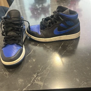 Nike Air Jordan 1 svart/blå sneakers - Säljer ett par Nike Air Jordan 1 sneakers i svart och blått skinn. Skorna har varit använt och har bara ett problem med snören men det kan bytas ut priset kan diskuteras vid snabb affär frakt funkar även.