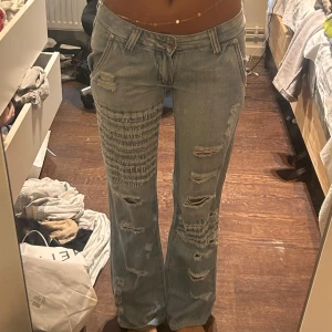 Lågmidjade Jeans med detaljer - Skit snygga och en av mina favorit byxor!! Jätte lågmidjade med massor av hål där bak och i framsidan!! Bra skick. Passar mig som har 26/27 i midja!