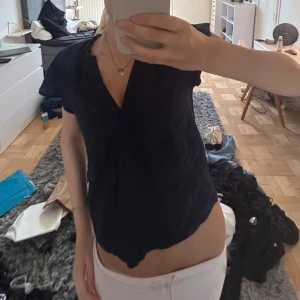 Mörkblå v-ringad blus med kort ärm - En mörkblå blus med v-ringning och korta ärmar. Modellen är lite lös och har en enkel, stilren look som passar till mycket. Tyget ser ut att vara mjukt och lätt, perfekt för varmare dagar.