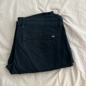 Mörkblåa italienska finbyxor från Sorbino - Snygga svarta kostymbyxor från Sörling med klassisk passform. Byxorna har hällor för bälte, bakficka med diskret metallogo och är tillverkade i ett mjukt bomullsmaterial. Perfekta för en clean och stilren look.