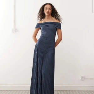 Marinblå offshoulder långklänning Lioness - Snygg marinblå långklänning med offshoulder och plisserad kjol. Överdelen är åtsittande med draperad effekt och kjolen har ett fint fall. Perfekt för dig som vill sticka ut med en elegant och modern look. Funkar även för gravid. Använd en gång.
