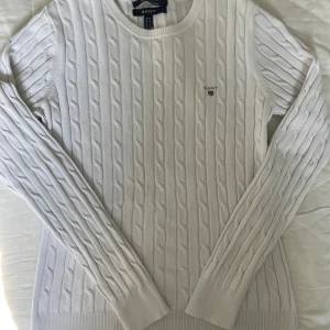 Vit kabelstickad tröja från GANT🤍 - Vit kabelstickad tröja från GANT i bomull med stretch! Klassisk rund halsringning, ribbade muddar och broderad GANT-logga på bröstet✌🏼. Hör av dig om du har någon fundering!💭