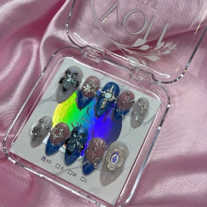 NE0DR1P (XS);Medium Almond - Snygga gelé lösnaglar i medium mandelform med blå, grå och nude bas. Naglarna är dekorerade med silvriga stjärnor, kors, pärlor och 3D-blommor samt holografiska detaljer. Perfekt för dig som vill sticka ut med unika och kreativa naglar. I storlek XS: 14 mm, 11 mm, 11,5 mm, 10 mm, 8 mm 