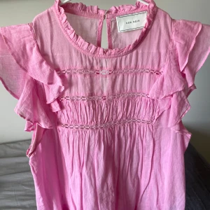 Rosa volangblus från Neo Noir - Supersöt rosa blus från Neo Noir med volangdetaljer på ärmarna. Blusen ser nästan helt oanvänd ut och är i en så fin färg. Köpt för 699 och finns inte att hitta längre. Perfekt för vår och sommar!