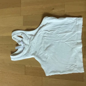 Vit ribbad linnetopp från Divided - Säljer en vit ribbad linnetopp från Divided. Toppen har en klassisk racerback-modell och är tillverkad i mjukt, stretchigt material. Perfekt till sommaren och enkel att matcha med olika outfits.