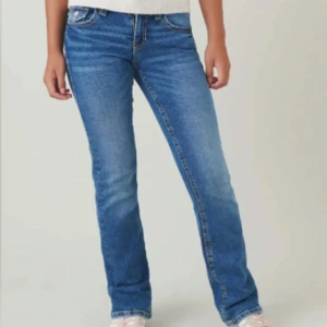 Blå bootcut jeans - Klassiska blå jeans med bootcut passform och normal midja. Jeansen har fem fickor och snygga sömmar, samt lätt slitning framtill och baktill för en avslappnad look. Perfekta till vardags med en enkel topp eller hoodie.  Hål vid zippen